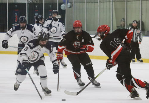 Image of Mitchell Cartwright on ice with teammates as they work to control the puck