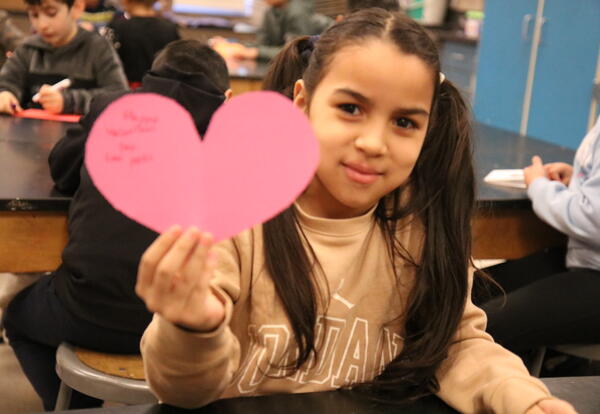 A student holds up a homemade valentine card.