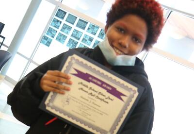 A student holds up her honor roll certificate.