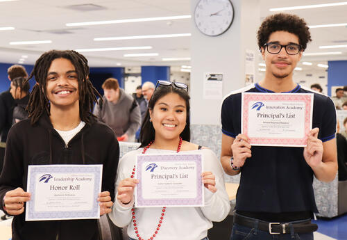 Three students holding their honor roll certificates