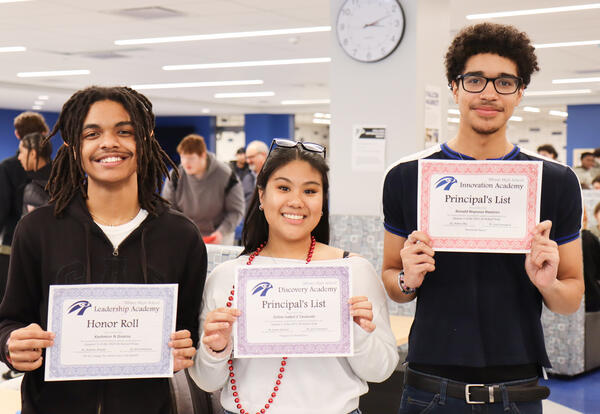 Three students holding their honor roll certificates