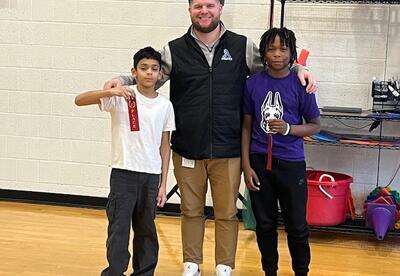 Two students and an administrator pose with ribbons they won.