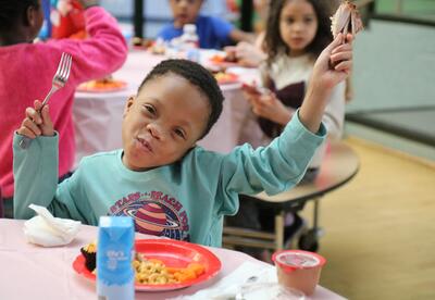 A student joyfully eats chicken.
