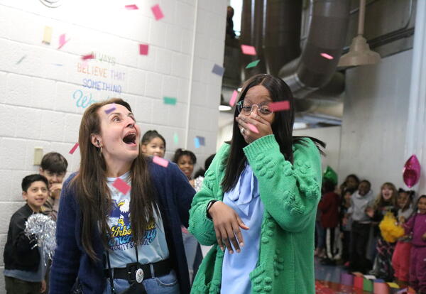 Confetti falls on an administrative team as students and staff cheer during a goodbye parade.