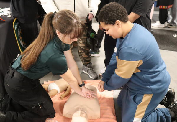 A student learns how to do chest compressions on a dummy.