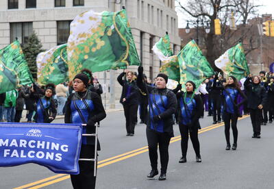 Photograph of student-musicians and color guard marching at the St. Patrick's Day parade
