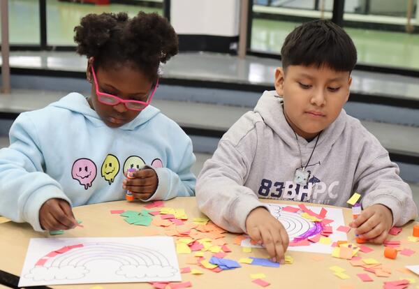 Two students work on a rainbow craft.