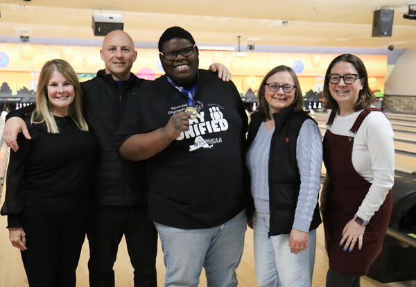 Unified bowling student-athlete posing with district staff