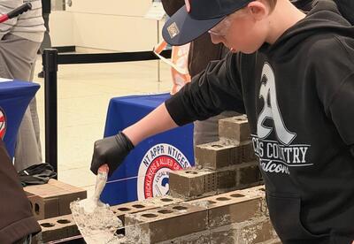 A student practices bricklaying with cement.