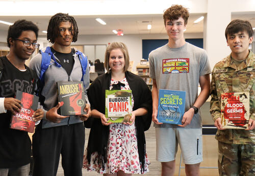 Four students with Albany High librarian holding copies of Jarrow's books