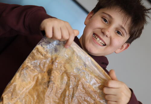 A student holds up a plastic bag with slime in it.