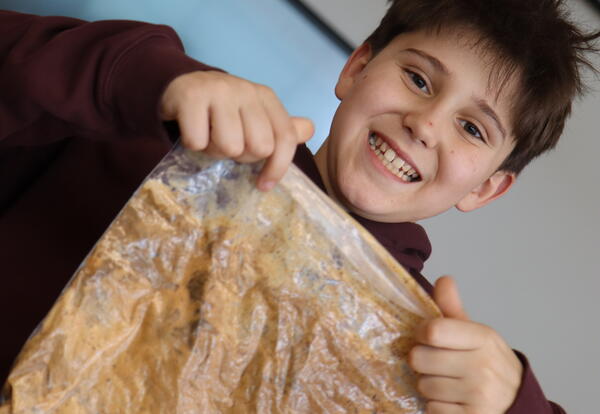 A student holds up a plastic bag with slime in it.