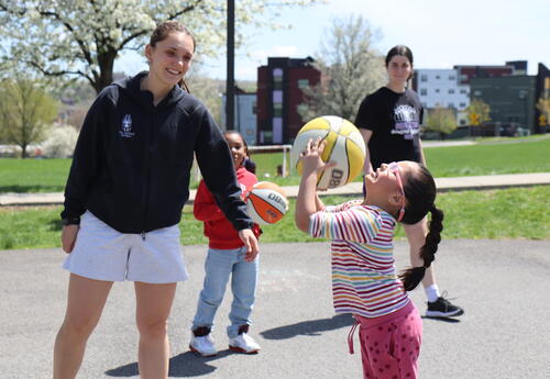 Uӣ����Ƶ basketball players help students learn to play the sport.