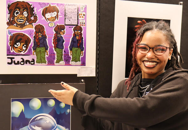 Student posing with artwork at the festival