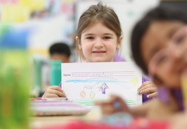 Student holding up their writing with an illustration of a bicycle