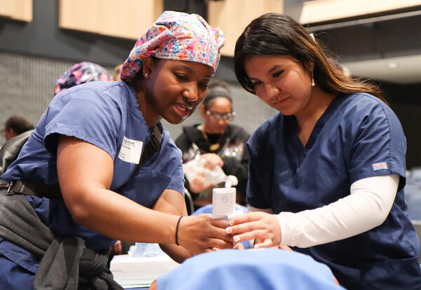 Shaneé Hoke showing a student the steps of intubation on a patient care manikin