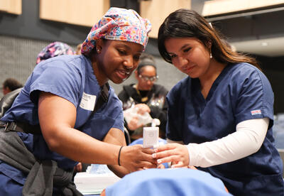 Shaneé Hoke showing a student the steps of intubation on a patient care manikin