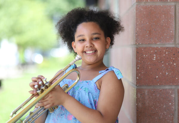 Student smiling while holding a trumpet