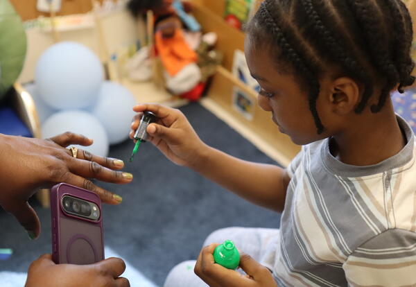 A student paints his mom's nails.