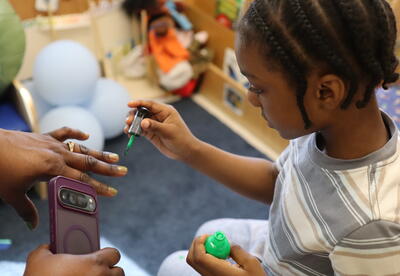A student paints his mom's nails.