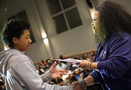 A students recieves his honor roll certificate from the principal.