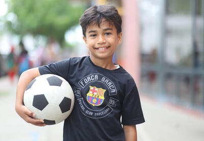 Student smiling and holding a soccer ball