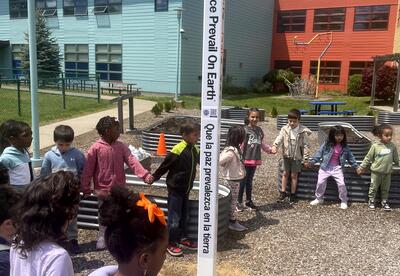 Students celebrate the installation of a peace pole on the Montessori playground.