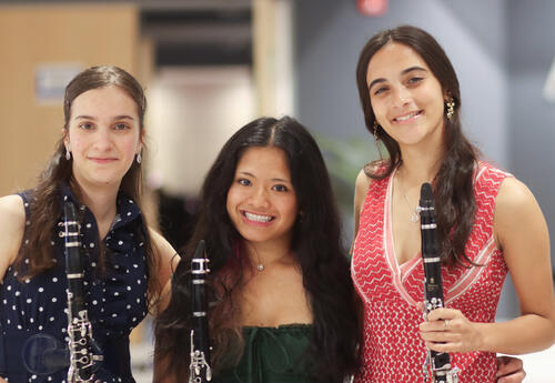 Three band students posing for a photo with their instruments