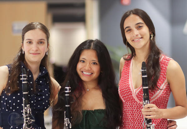 Three band students posing for a photo with their instruments