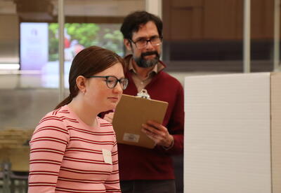 A student presents her science fair project to a judge.