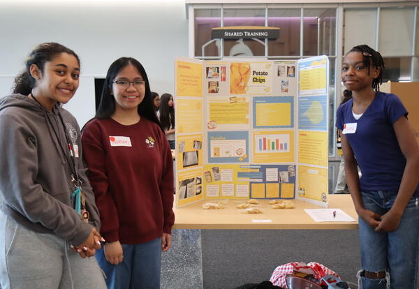 Three students present their science project to a UAlbany representative.