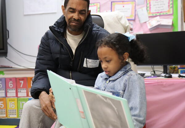 A student reads to her father.
