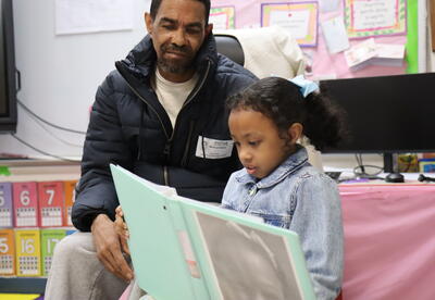 A student reads to her father.