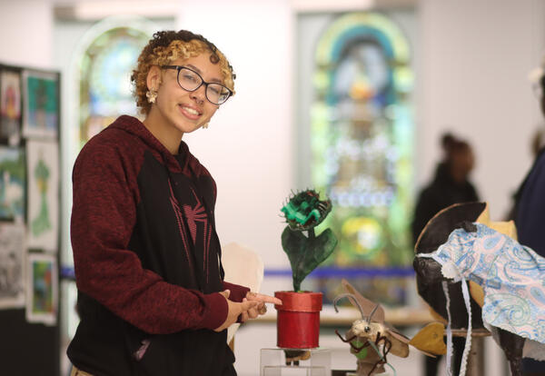 Student posing with artwork