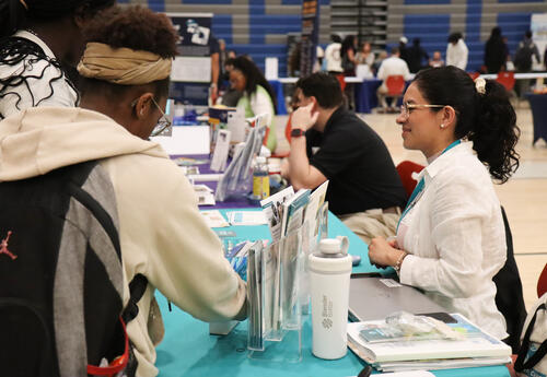 Students speaking with a representatives at a table