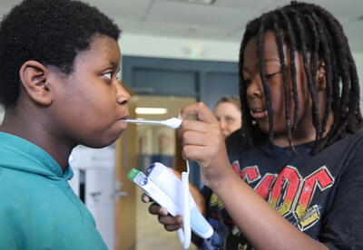 A student takes another student's temperature.