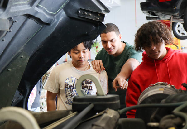 Three students looking under the hood of the HMMVW