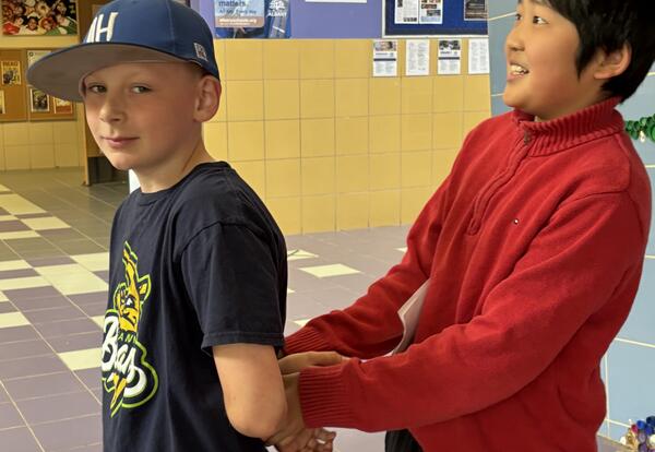 A student pretends to escort out another student in handcuffs.s.