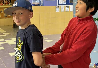 A student pretends to escort out another student in handcuffs.s.