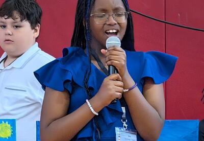 A student sings a song during an assembly.