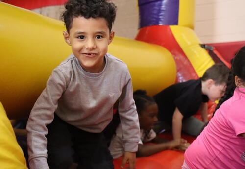 A student crawls through a bounce house during field day.