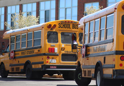 Yellow school buses wait to pick up students outside school