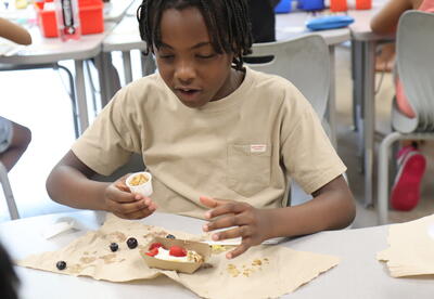 A student makes a banana split with yogurt.