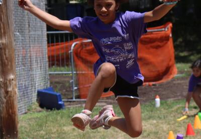 A student jumps over a hurdle during Field Day.
