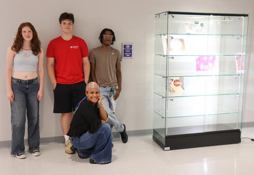 Art students standing by new display case and commemorative sign