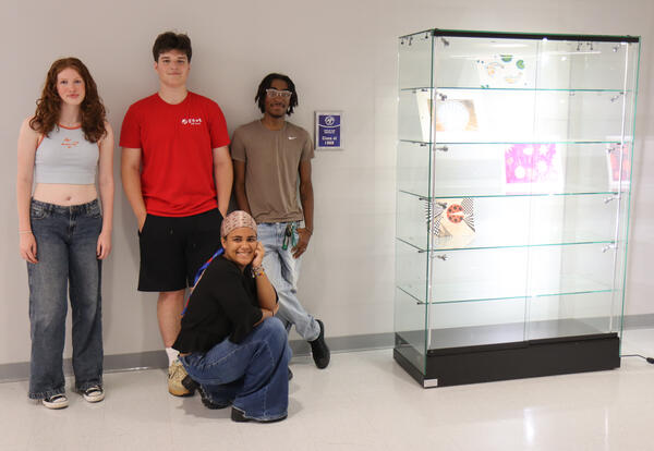 Art students standing by new display case and commemorative sign