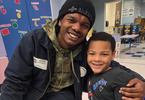 A father and his son pose at a Father's Day event.