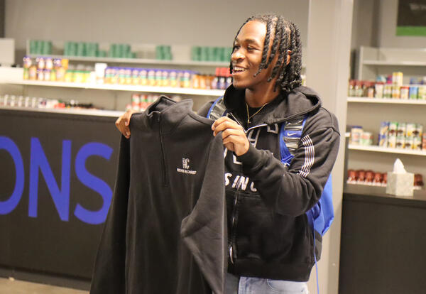 Campbell holding up a shirt that was part of his donation to the Falcon Market
