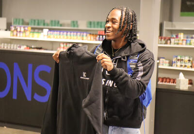 Campbell holding up a shirt that was part of his donation to the Falcon Market
