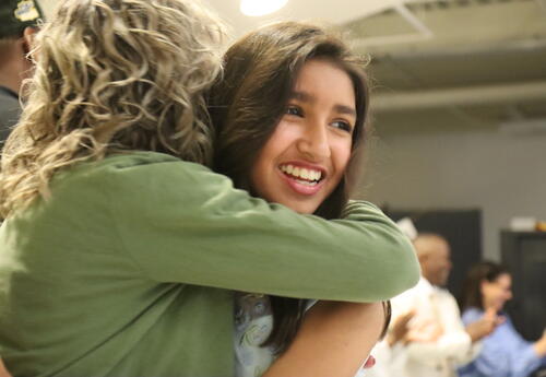 A student hugs her teacher at a moving up ceremony.